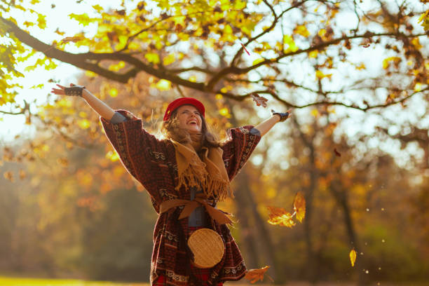 istock happy stylish female in red hat throwing autumn leafs 1716980782