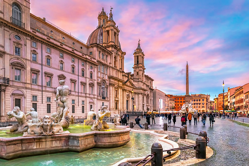 Piazza Navona in Rome Italy, crowded with tourists, on a winter day, just before sunset. In the foreground the famous Fontana del Moro.