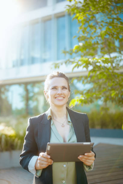istock happy modern female worker near office building using tablet PC 1717026783