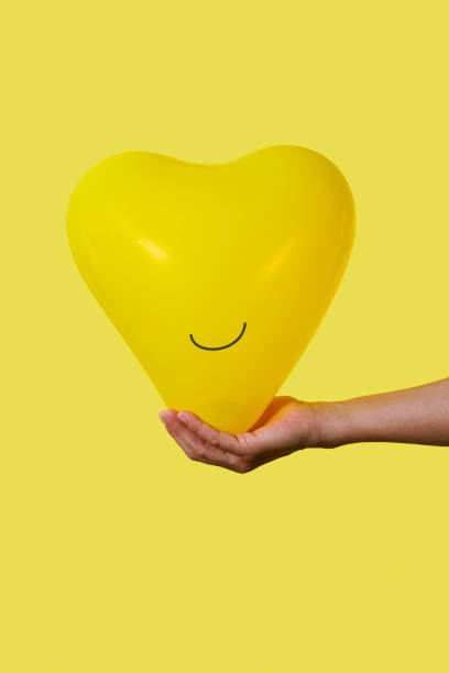 istock man holding a smiley yellow balloon 1717028453