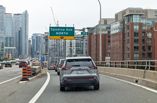 Toronto, Canada - August 24, 2023: Eastbound traffic leaves the Gardiner Expressway at Exit 153 to Spadina Avenue North. Overcast afternoon in summer in the CityPlace neighbourhood lined with upscale residential buildings.