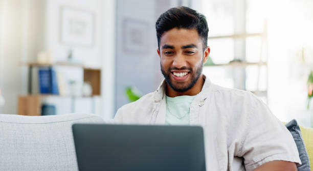 istock Laptop, laughing and man on couch watching funny video, live streaming or reading post on social media. Happy person relaxing on sofa with computer, internet and wifi in his apartment or living room 1717053143