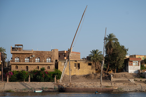 Houses along the Nile River, a sailboat on the riverbank in Aswan, Egypt
