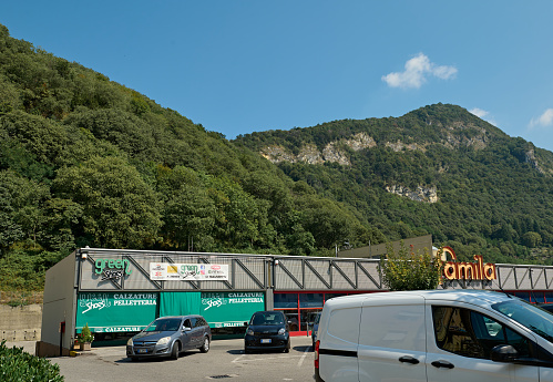 Cars parked in the outdoor parking places in modernized medieval Italian Canzo city, against Alp mountains background. Italy. Lombardy. September 2023. Tourism. Travel destinations