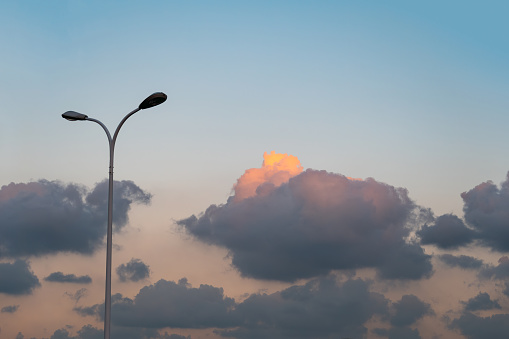 A streetlight at summer dusk and clouds in the sky.