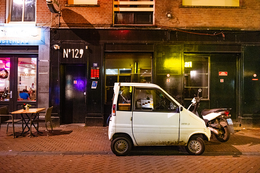 In Amsterdam, Netherlands a white Canta accessibility vehicle is parked alongside a pedestrian street at night.