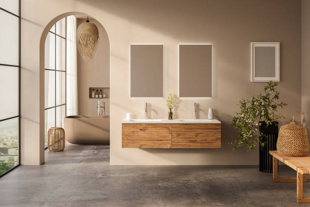 Beige bathroom interior with white basin and double mirror, concrete floor, bathtub, plants. Bathing accessories and window in hotel studio.