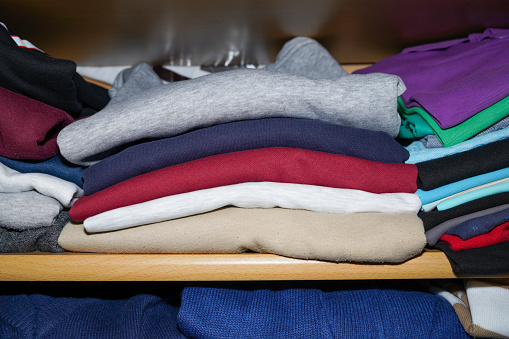 Wardrobe overflowing and colorfully mixed with jackets and pants, sweaters and bags