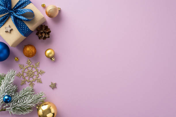 istock Whimsical holiday spirit: Top view shot featuring charming giftbox with bow, gleaming baubles, pine cone amidst snowflake and fir branch on a pastel purple canvas, ideal for greeting text or adverts 1717118421