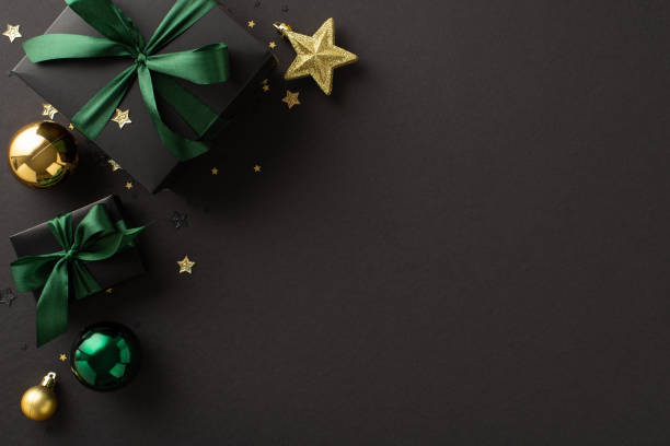 célébrez l’arrivée du nouvel an dans un style opulent, avec des photos de haut de boîtes cadeaux noires de luxe avec des nœuds verts, des boules dorées et vertes, un ornement étoilé, des confettis, une surface noire avec espace publicitaire - confetti gold black star shape photos et images de collection