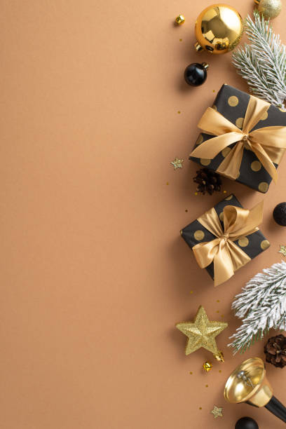 istock Experience magic of Christmas with this setup. Vertical top-down view of beautifully wrapped presents, tree decor, glistening confetti, bell, frost-kissed fir branches on terracotta with room for text 1717118486