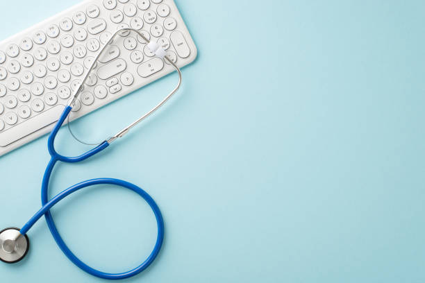 istock Experience modern healthcare through virtual visits. Top-down view of a pc keyboard and stethoscope for checkup arranged on a pastel blue backdrop, awaiting your customization 1717118498