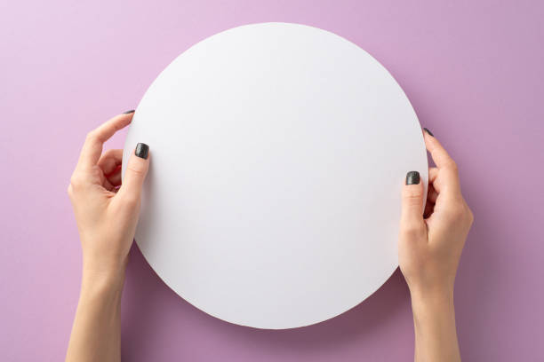 istock Creative promo image: First person view of female hands, adorned with chic black manicure, elegantly display white circular frame. On lilac backdrop, perfect for text or ads, it exudes style and charm 1717119058
