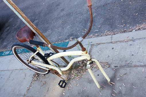 Broken rusted bicycle without front wheel locked to a roadside pole at 15-min parking place