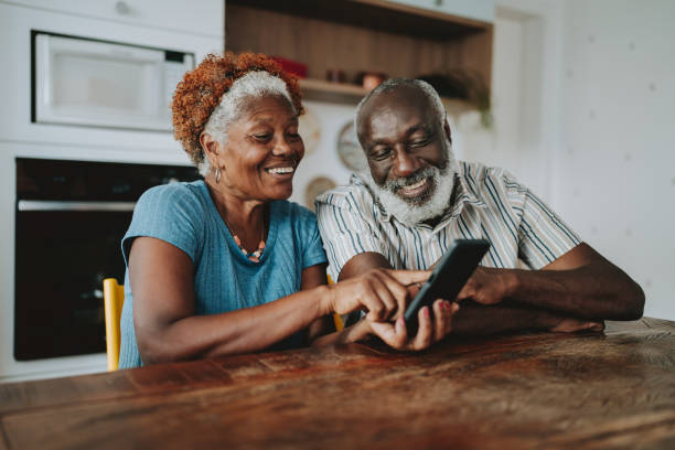 自宅でスマートフォンを使うポートレート老夫婦 - men laughing african descent color image ストックフォトと画像