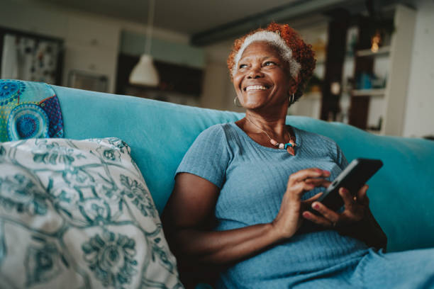 retrato de mujer mayor usando smartphone sonriendo - surfista de plata fotografías e imágenes de stock