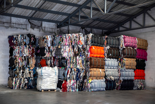 Heap of pressed colorful textile waste packed in bales in store-house