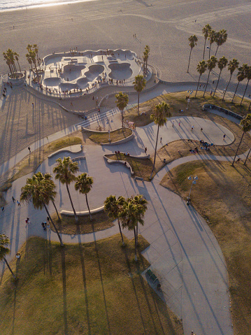 Aerial photos of the Venice Beach Skate Park taken with a drone during sunset. Long shadows of palm trees and skateboarders.