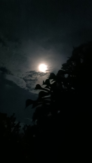 A full moon hidden behind the black clouds in the dark