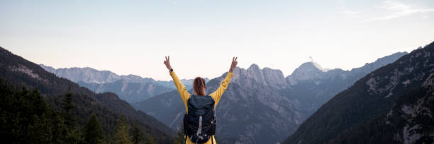 istock Hiker with backpack standing with raised arms looking at amazing mountain view 1717158733