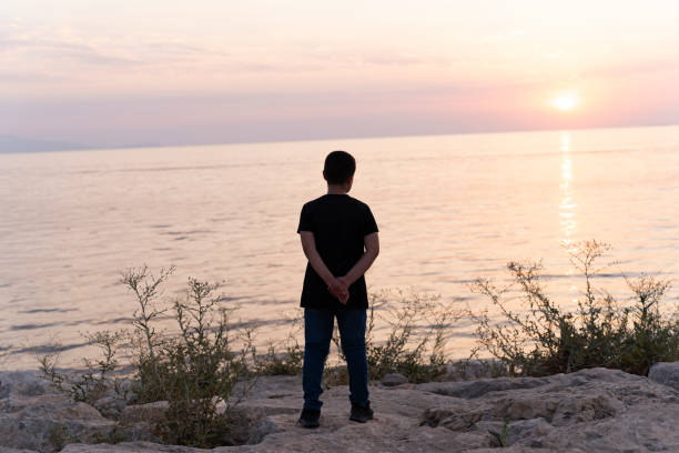 istock Sunset and a boy by the sea. 1717159907