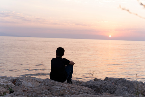 Sunset and a boy by the sea.