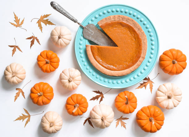 Top view of pumpkin pie on plate surrounded by mini pumpkins