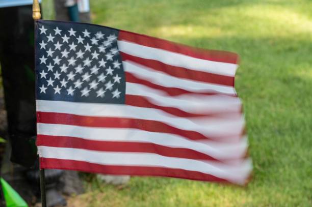 Motion blur fluttering graveside American flag in grassy cemetery