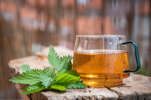 Cup of tea with nettle on a wooden table. Organic, natural drink and glass cup