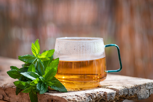 Cup of tea with mint leaves on a wooden table. Organic, natural drink in glass cup