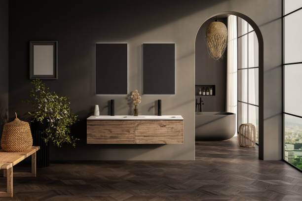 istock Stylish gray bathroom interior with parquet floor, window with mountain view, dark wall, big bathtub, and white basin with vertical mirrors and wooden vanity. 1717191303