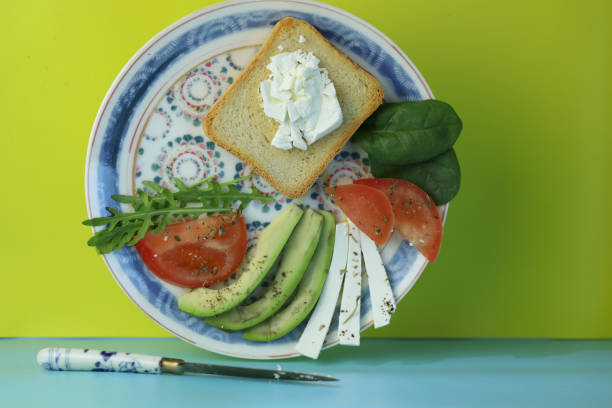 Toast with sliced avocado, cheese, tomato and spinach