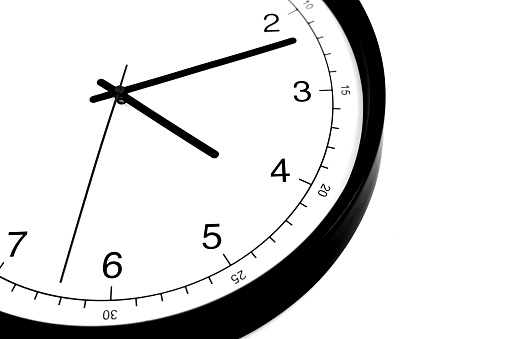 Part of analogue plain wall clock on white wall background. Four o'clock twelve minutes. Close up with copy space, timing, time management, opening hours time, school concept and lunch time