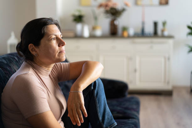 istock A woman  sitting alone on a sofa looking through the window 1717212579
