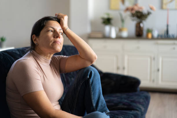 istock A woman  sitting alone on a sofa looking through the window 1717212583
