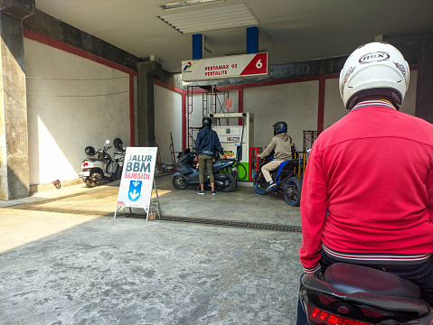 queue of people to fill up motorbike petrol at the Pertamina gas station