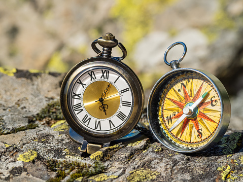 A person holding a small golden compass at the beach. Heading concept