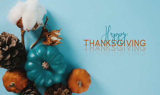 Blue and orange pumpkins for fall season flat lay with Happy Thanksgiving greeting on background.
