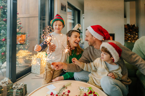 The joy of Christmas Photo of a family with two young children celebrating Christmas; holding sparklers and enjoying the lovely Christmas Eve together. family christmas party stock pictures, royalty-free photos & images