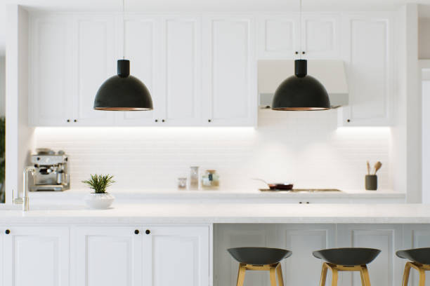 istock White kitchen with countertop as an accent. Kitchen work area with lamps, chairs and kitchen appliances. Kitchen with backsplash lighting blurred in the background. 3D rendering 1717263248