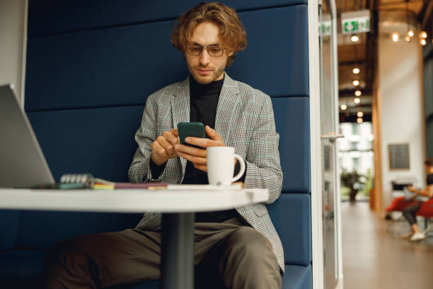 istock Handsome male freelancer holding phone while sitting in office during break time 1717268791