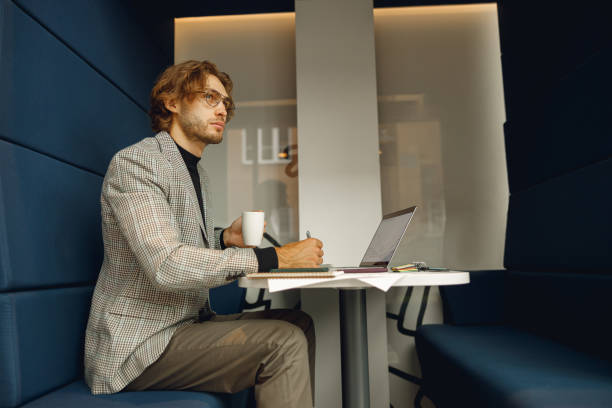 istock Handsome male freelancer making notes during working on laptop sitiing desk in coworking 1717269400