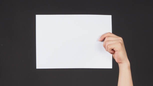 istock Male hands is holding the A4 paper on black background. 1717273844