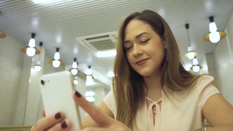 Beautiful camera shot of woman with cell phone in hand sitting in brightly lit public space
