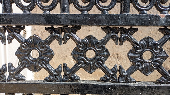 Part of the gate is made of forged metal with patterns, painted black photo