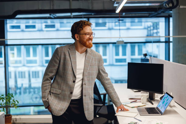 istock Smiling entrepreneur working with documents standing near desk in modern office 1717287688