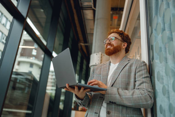 istock Handsome entrepreneur working on laptop standing in modern coworking during working day 1717299151