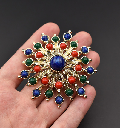 A timeless touch of elegance: A vintage gold brooch gracefully adorns a woman's hand, epitomizing retro charm and serving as the perfect promotional image for an online jewelry store.