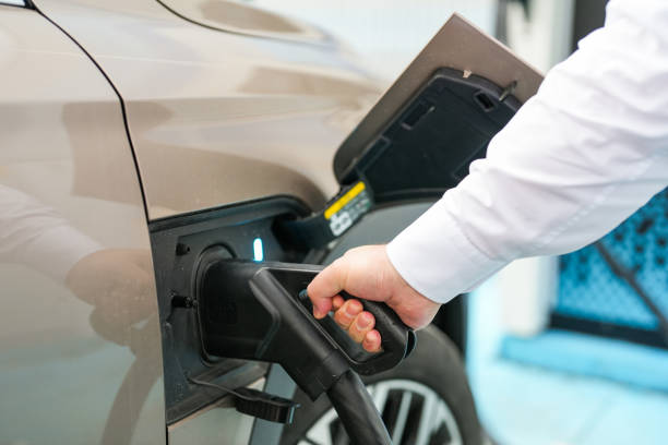 istock Man inserts a power cord into an electric car for charging 1717360248