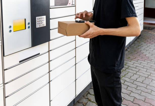istock A man with a box in his hands near the self-service mail terminal. Parcel delivery machine. Person holding a cardboard box. Mail delivery and post service, online shopping, e commerce concept 1717371977